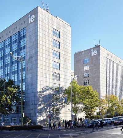 A modern university campus with glass buildings and trees in a clear blue sky.